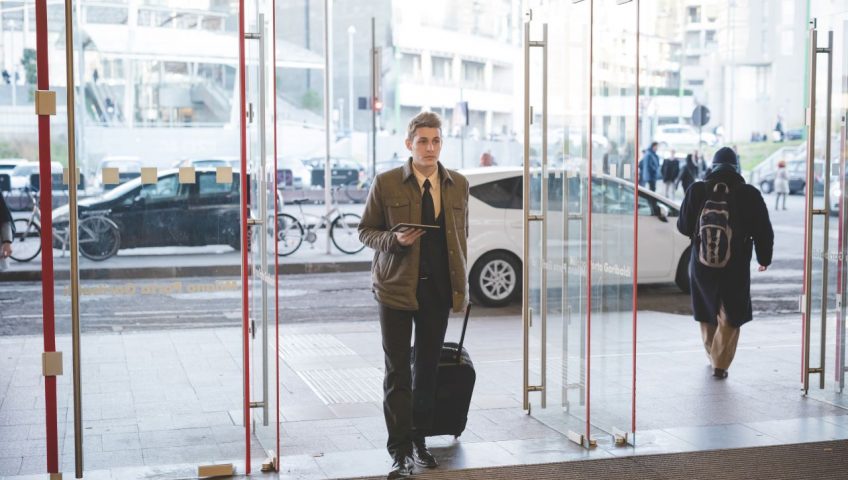 automatic door system, a man walking through glass doors with a suitcase