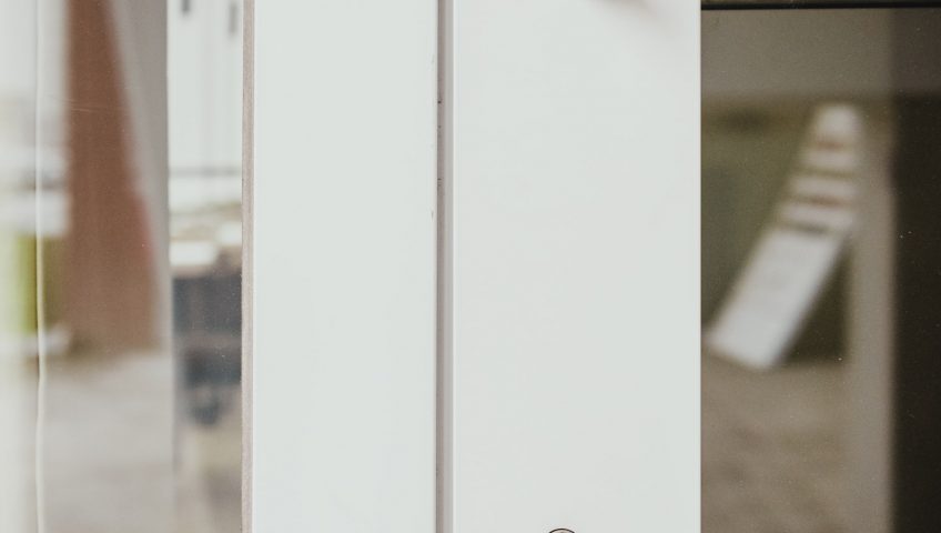 commercial door locks; A small keyhole on a white frame of a door.