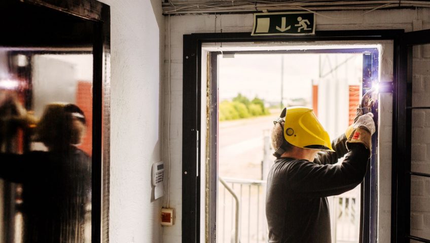 commercial door servicing, Man welding door frame