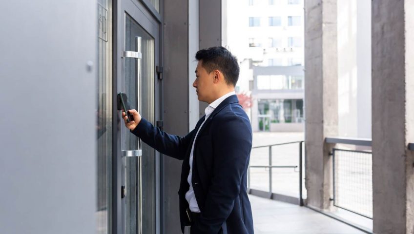 protecting business assets, an employee using his phone to tap on his office door