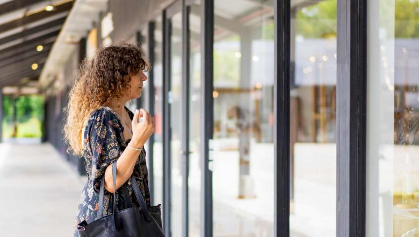Woman standing outside a commercial glass entrance waiting for an automatic door to open